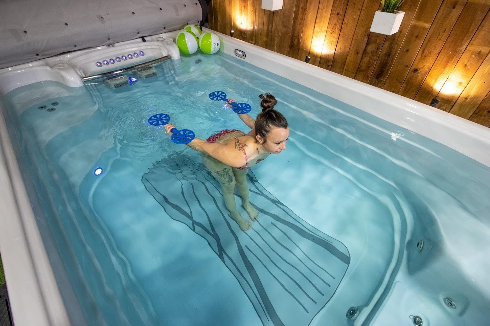 A woman in a swim spa having fun doing aqua aerobics.