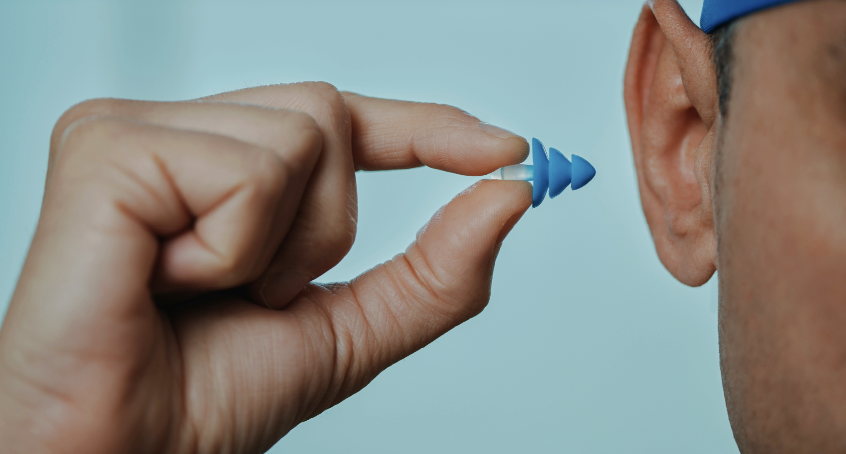 A man inserting a silicone ear plug for swimming.