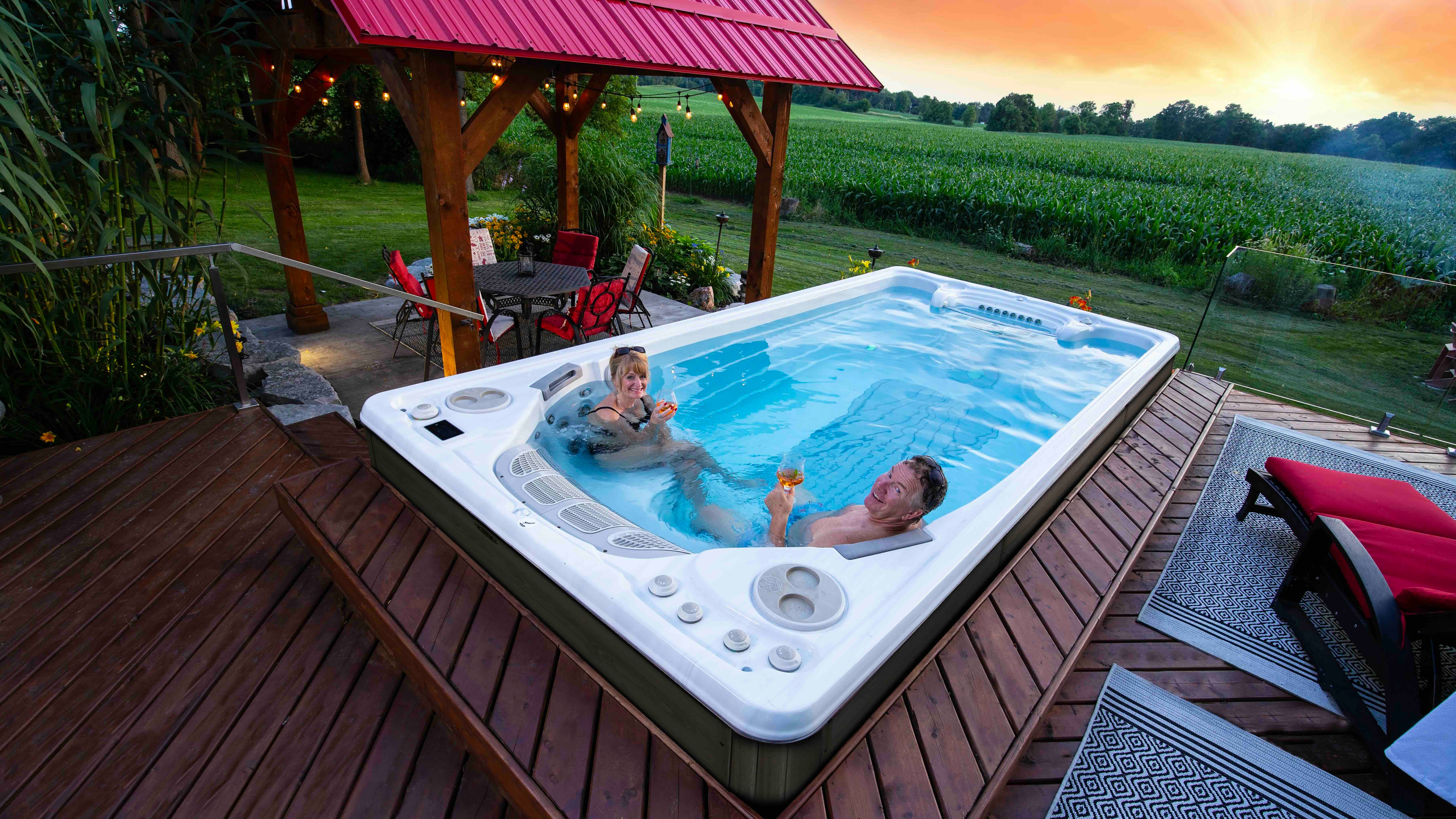 Above grade freestanding swim spa with a wooden deck and steps built around it.