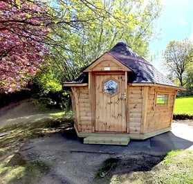 A BBQ Cabin with a blossoming pink tree next to it, to be used as a school room.