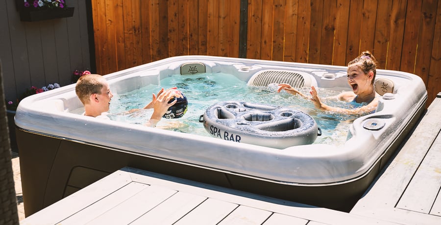 Two kids play in a Serenity hot tub on a sunny day.