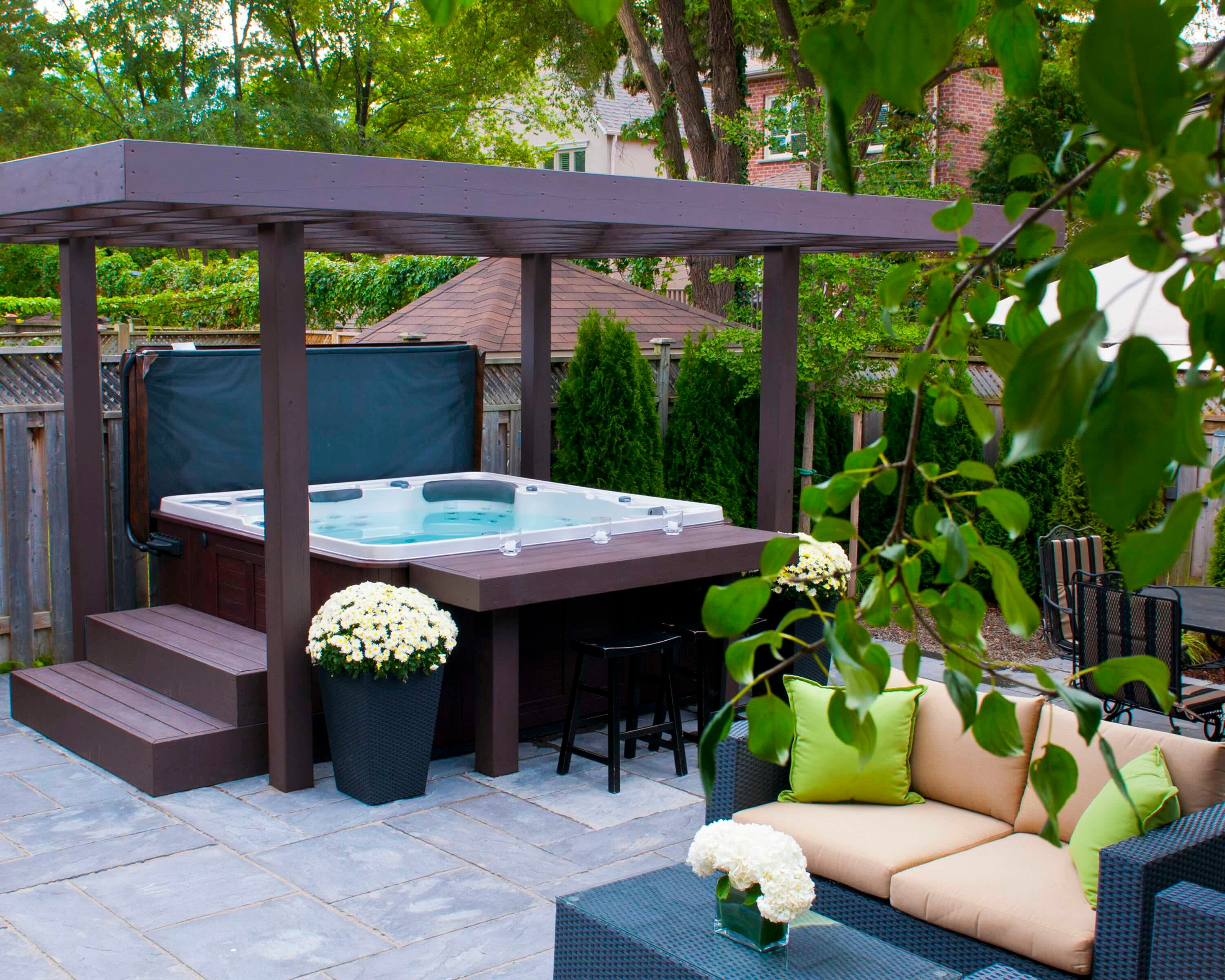 A hot tub with wooden pergola, steps, and bar that all match in a burgundy colour.