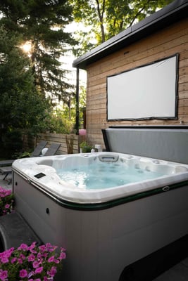 An above ground hot tub in a small garden, set against a house.