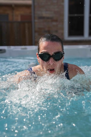 A woman swims intensely in her garden resistance swim spa.