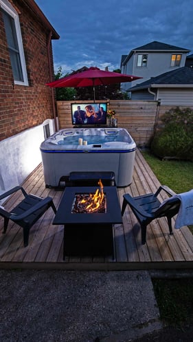 A romantic hot tub set up with nearby firepit and tv.