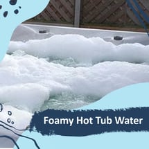 A hot tub with huge suds of foam on top of the water.