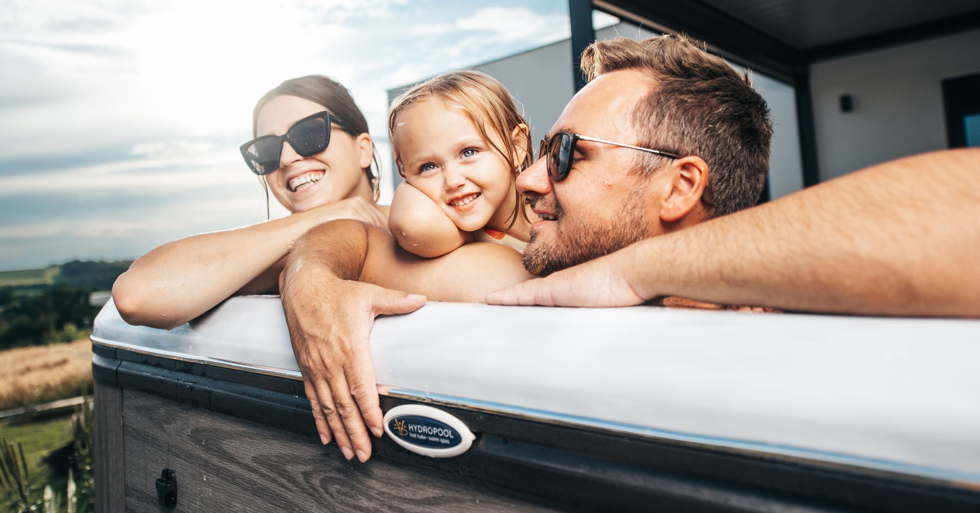 A mother, father, and daughter enjoy their Hydropool hot tub, showing a Hydropool is for all generations.