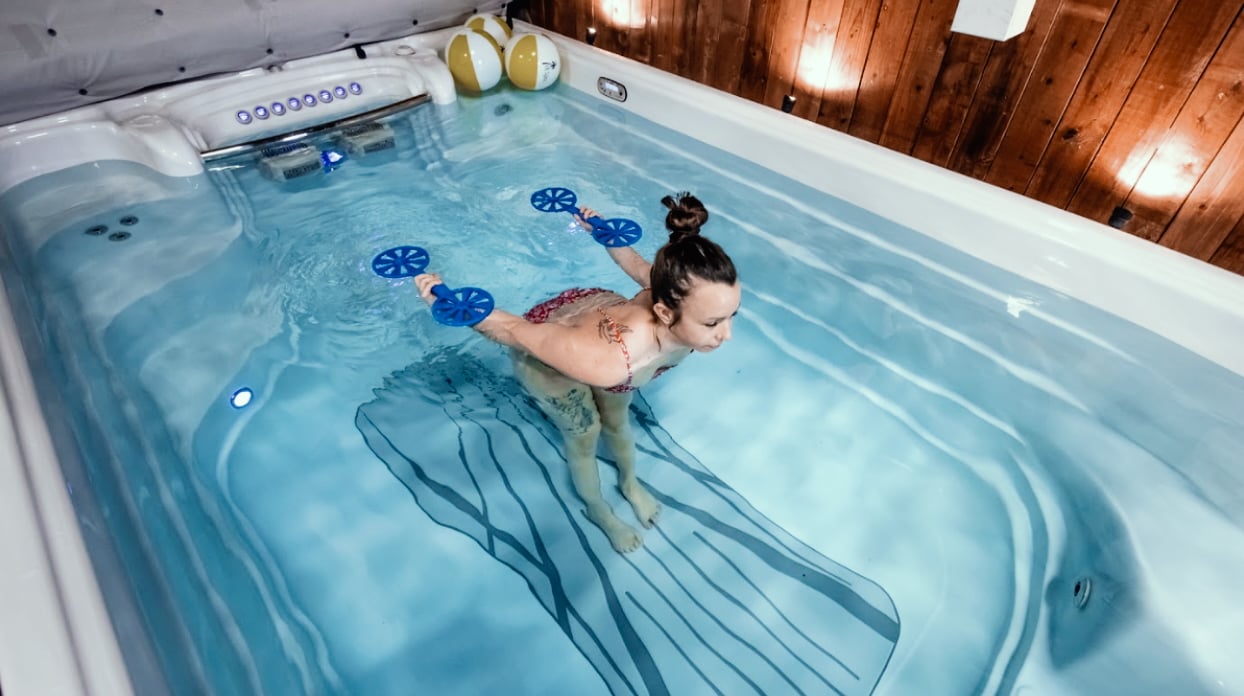 A young lady using a Hydropool swim spa to do some light exercising, showcasing that swim spas are suitable for all ages and abilities.