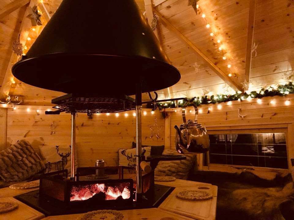 The fairylighted interior of an arctic grilling cabin.