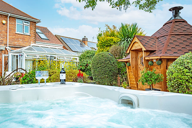 A BBQ Cabin in the background of a bubbling hot tub from Hydropool North West.