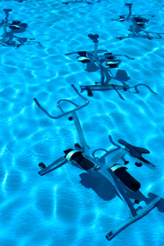 4 aquacycle bikes photogrpahed from above in bright blue water.