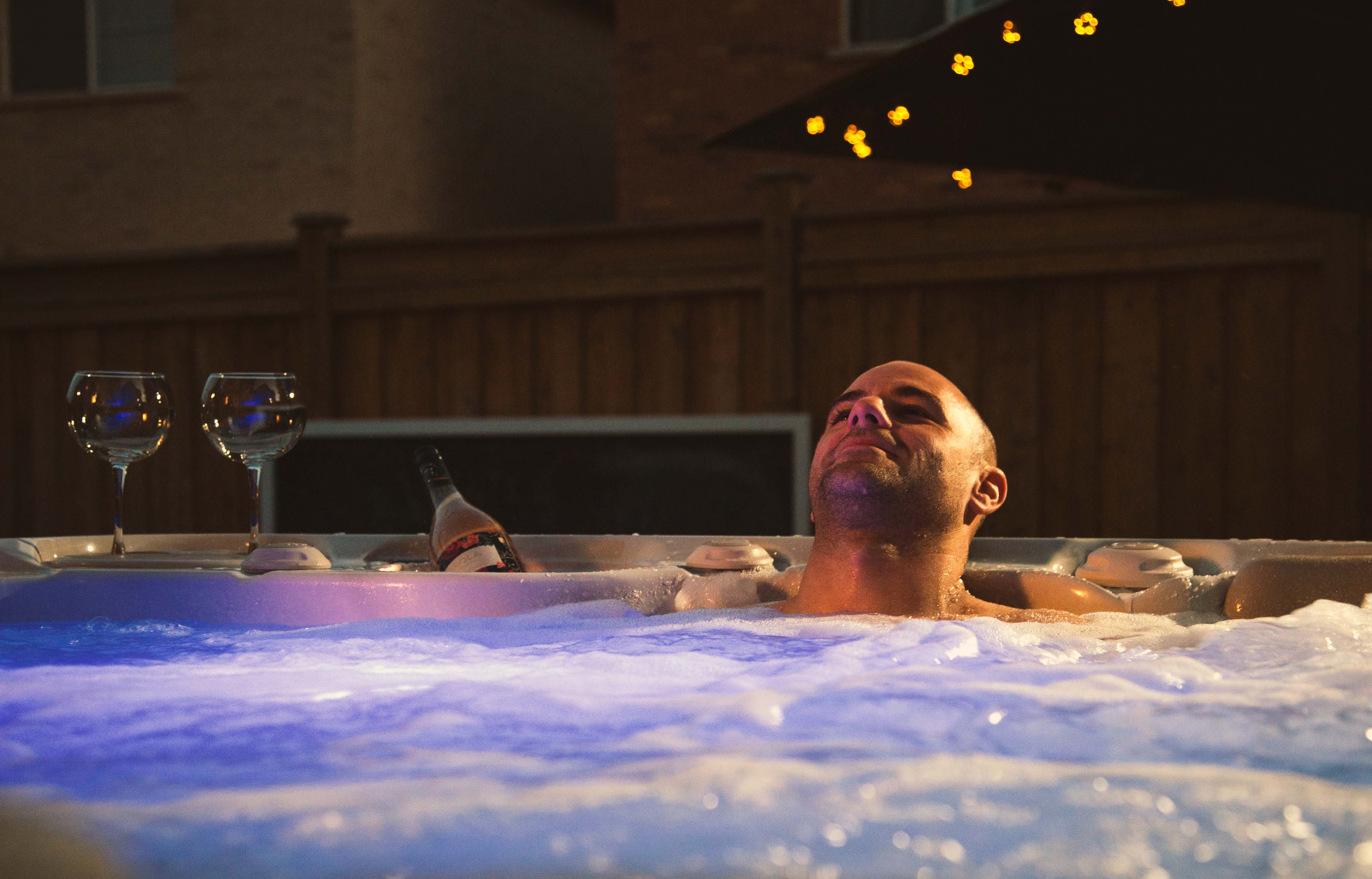 A man practices hydrotherapy at home, relaxing in his Hydropool Hot Tub at night. 