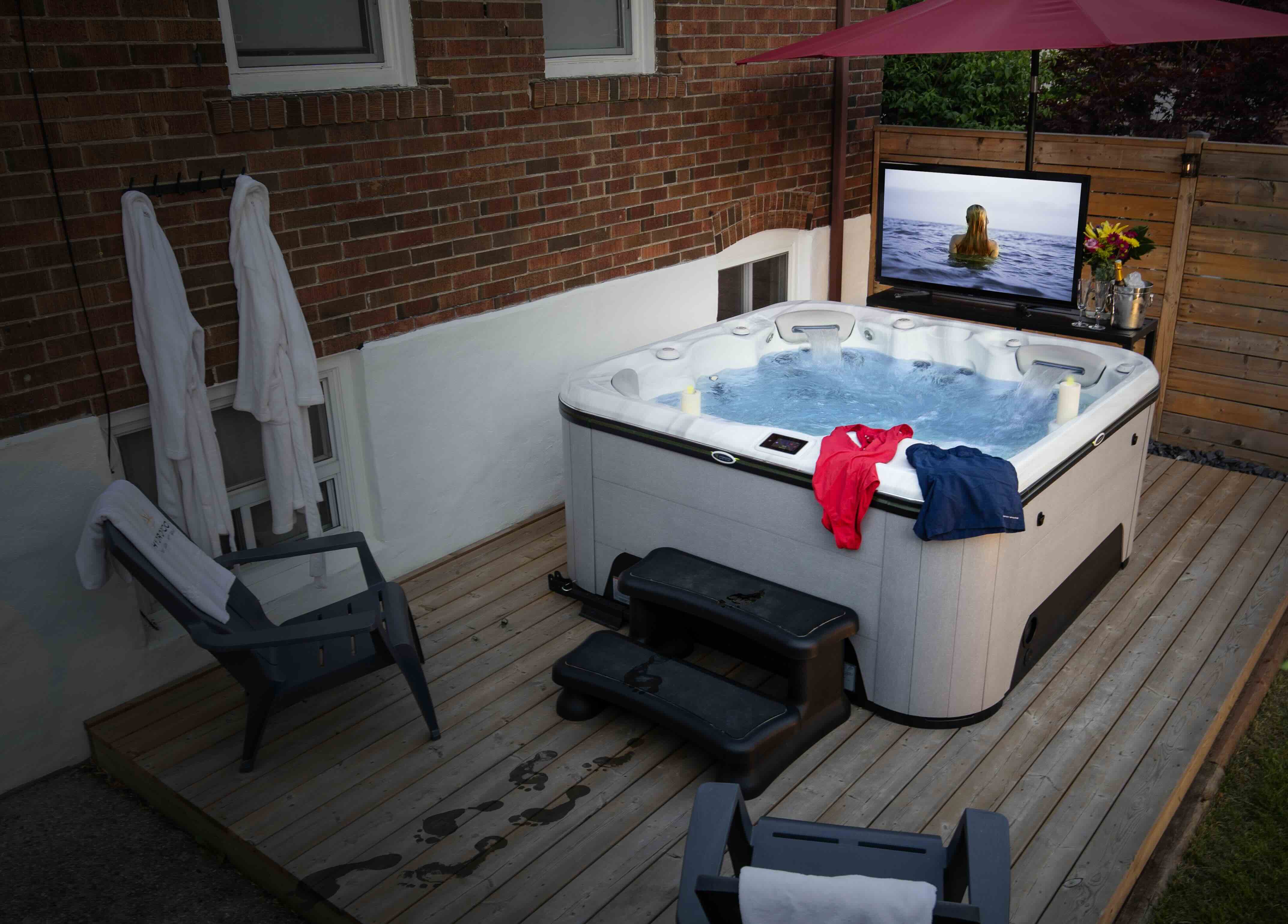 A hot tub set up for the perfect hot tub date with a tv and bathrobes ready for after. 